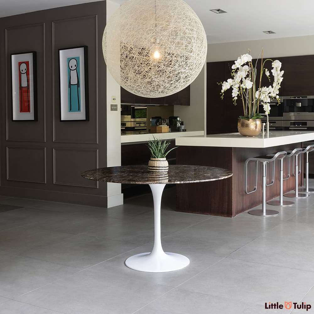 In the centre of a dark wood modern kitchen we see this 120 emperador round Tulip table under the hanging ceiling light