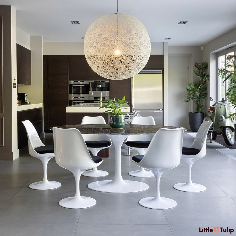 Under a large globe light, the 200 emperador tulip table and 6 chairs with black cushions exhibit unmatched style.