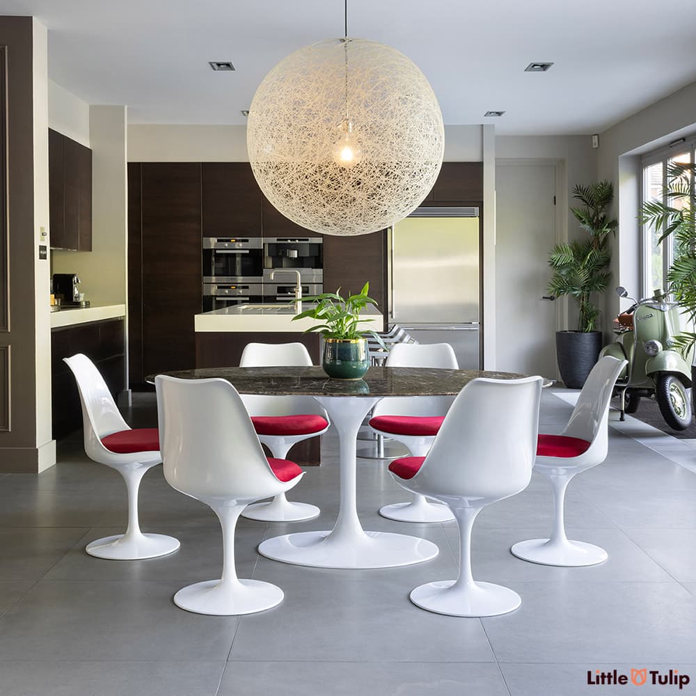Under a large globe light, the 200 emperador tulip table and 6 chairs with red cushions exhibit unmatched style.
