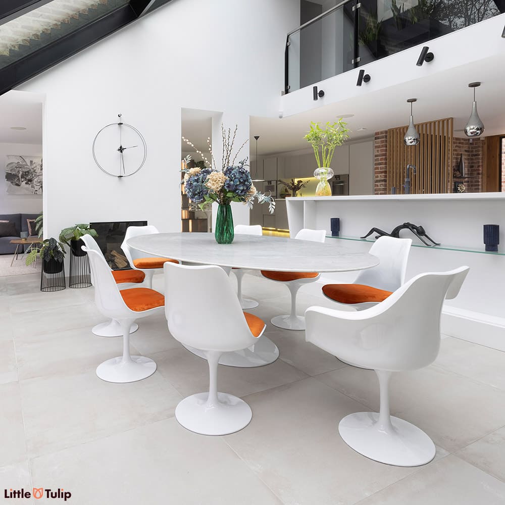 Complementing the all-white open plan space is this 244 Carrara Tulip table and 2 arm, 6 sides with their orange cushions