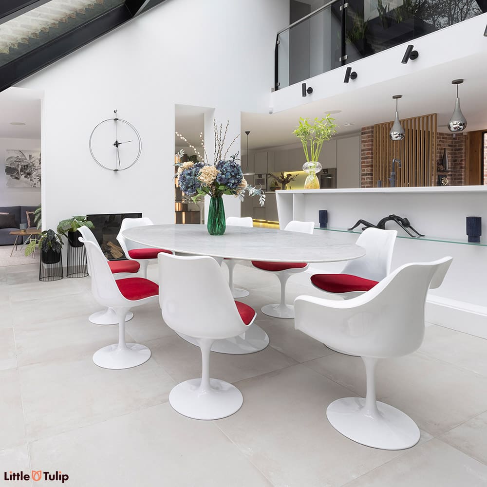 Complementing the all-white open plan space is this 244 Carrara Tulip table and 2 arm, 6 sides with their red cushions
