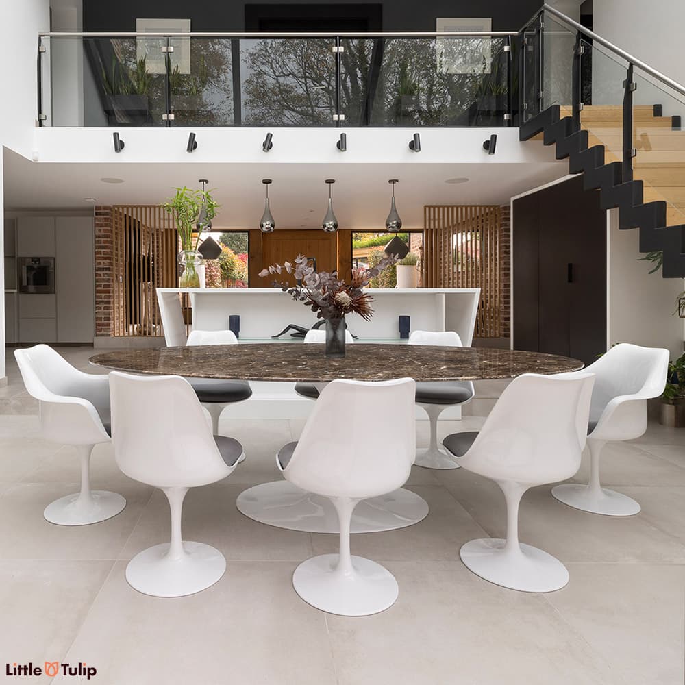 An eye-catching 244 Emperador Tulip table with 6 side, 2 arm chairs and grey cushions in a modern open-plan kitchen