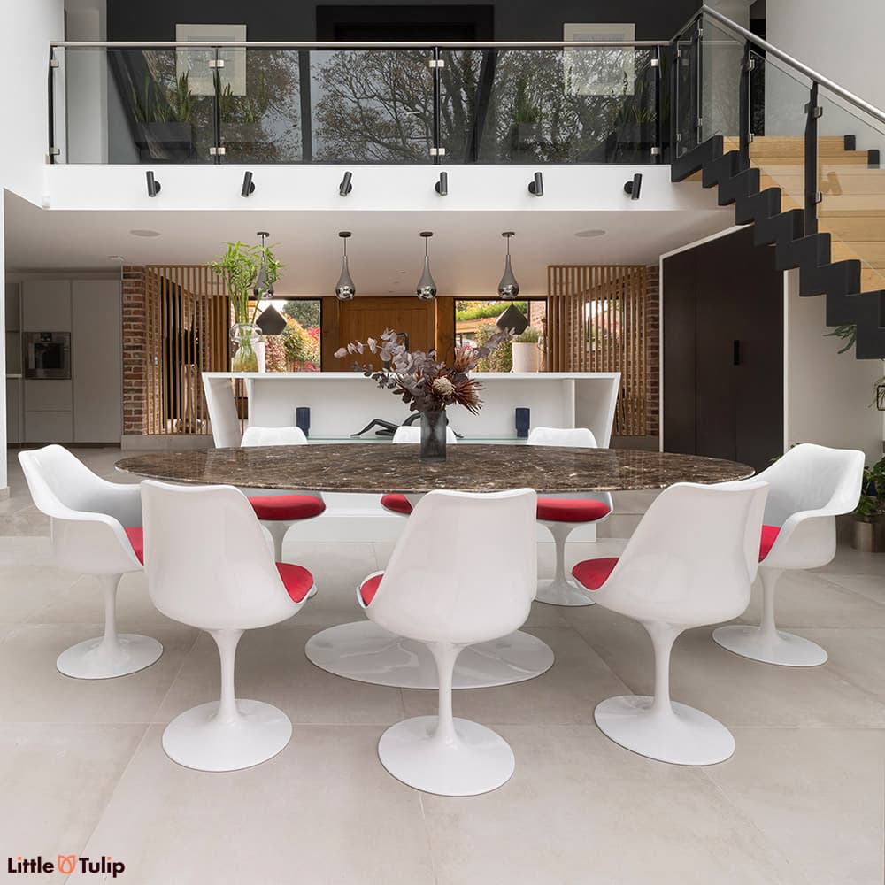 An eye-catching 244 Emperador Tulip table with 6 side, 2 arm chairs and red cushions in a modern open-plan kitchen