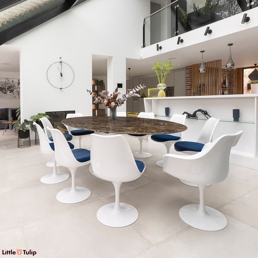 This luxurious emperador 244 tulip table with 8 side and 2 arm chairs with blue cushions enriches this all-white kitchen