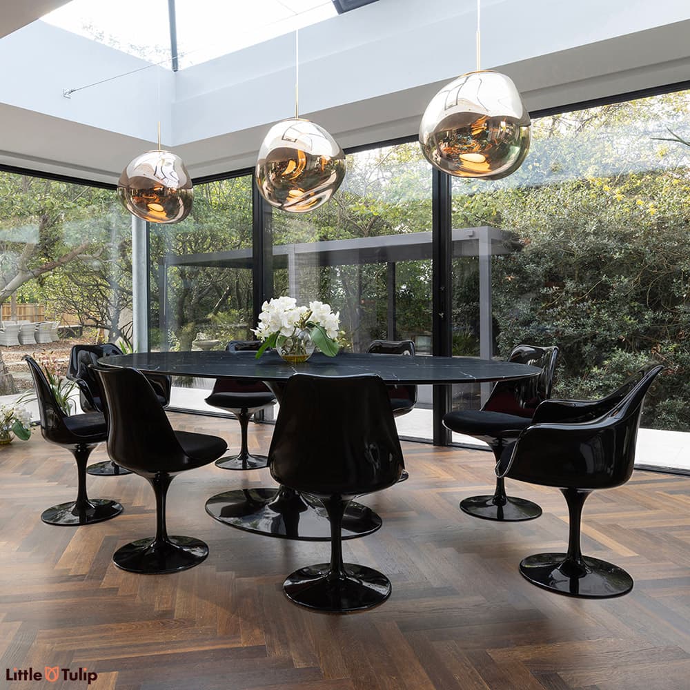 In a wonderfully lit dining space is this neromarquina 244 Tulip table and its 6 side, 2 arm chairs with black cushions