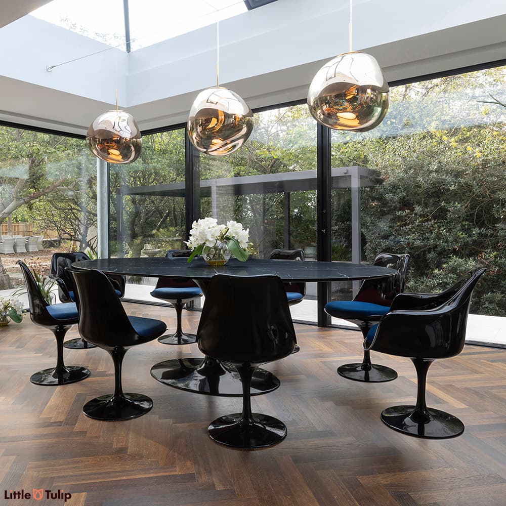 In a wonderfully lit dining space is this neromarquina 244 Tulip table and its 6 side, 2 arm chairs with blue cushions