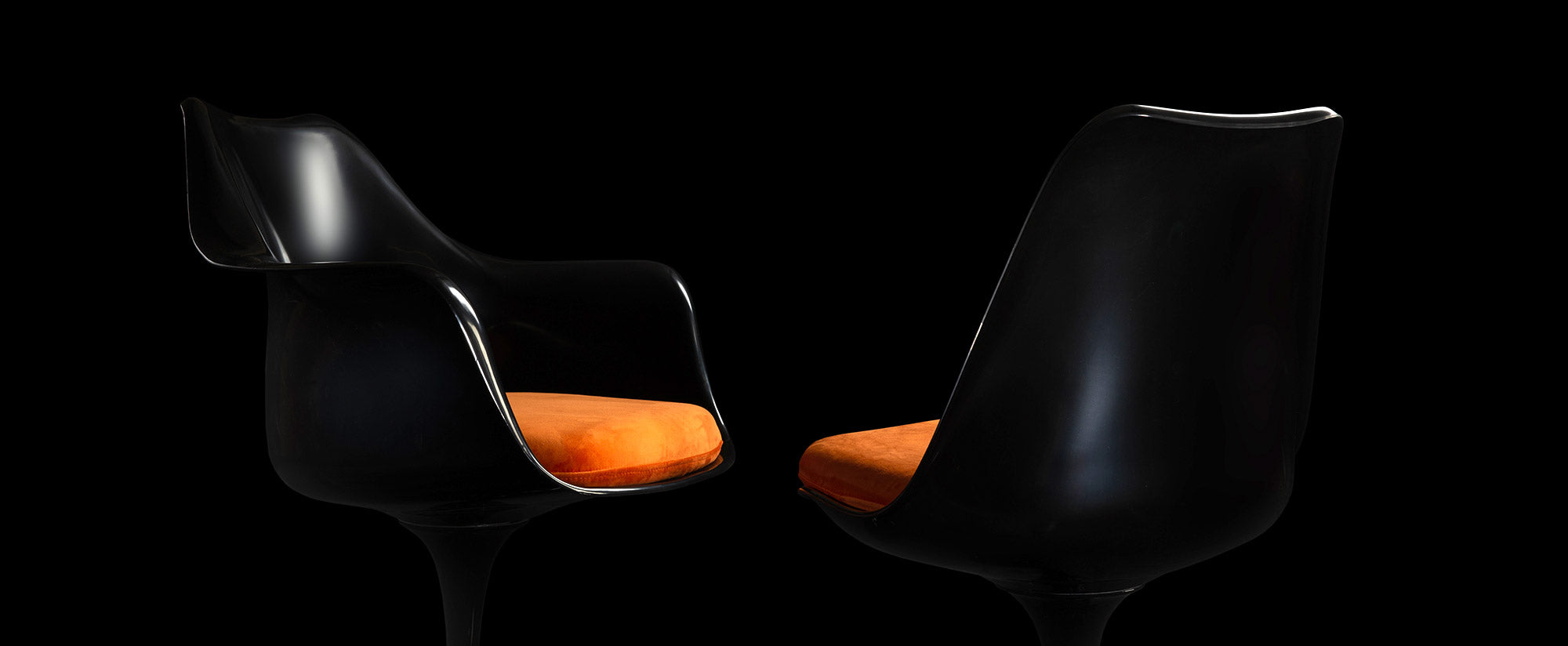 With a special mood and minimal lighting, a black Tulip Side and Arm chair can be seen as a silhouette & a splash of orange form the cushions