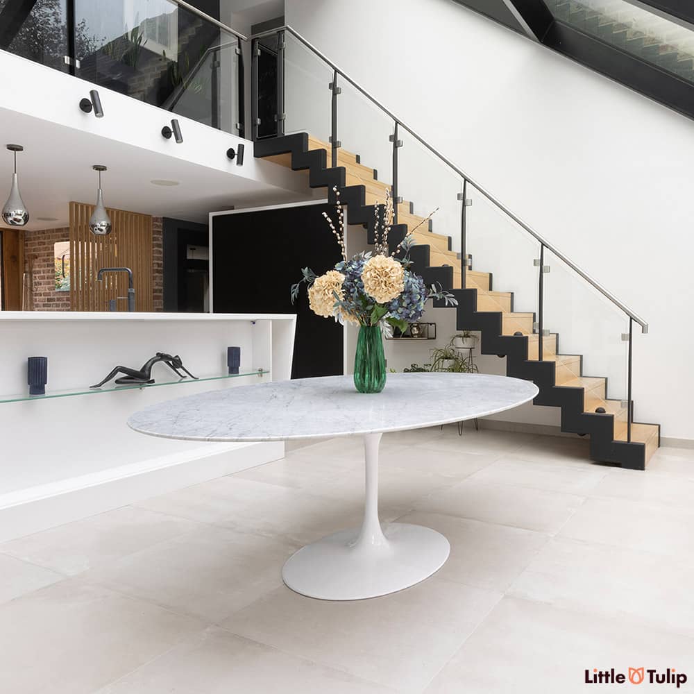 The subtleties of the classic White Carrara Marble can be seen across this super large oval 244 cm Tulip Table within a highly modern dining room setting