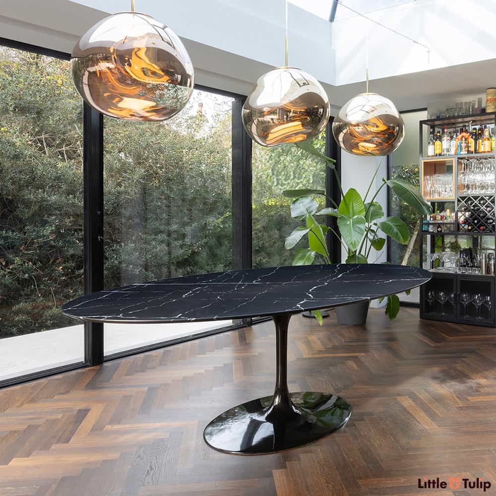 Not for the feint hearted the black Nero Marquina marble topped 244 x 137 oval Tulip Table add a darker touch to this modern glass lined dining room