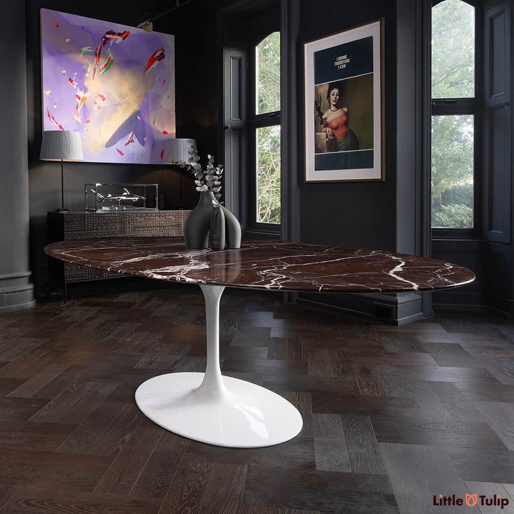 A very large oval 244 cm Tulip Table seen in the majestic Rosso Levanto red Marble and set within a beautiful quirky but classic wood paneled dining room 