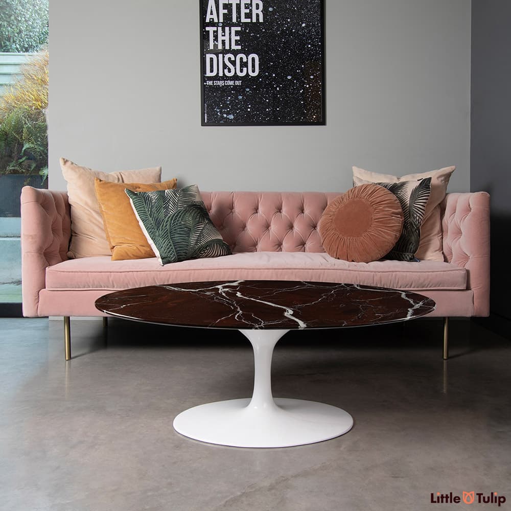 Sitting in front of a pink sofa is a lovely levanto rosso Saarinen oval coffee table with its deep red luster.