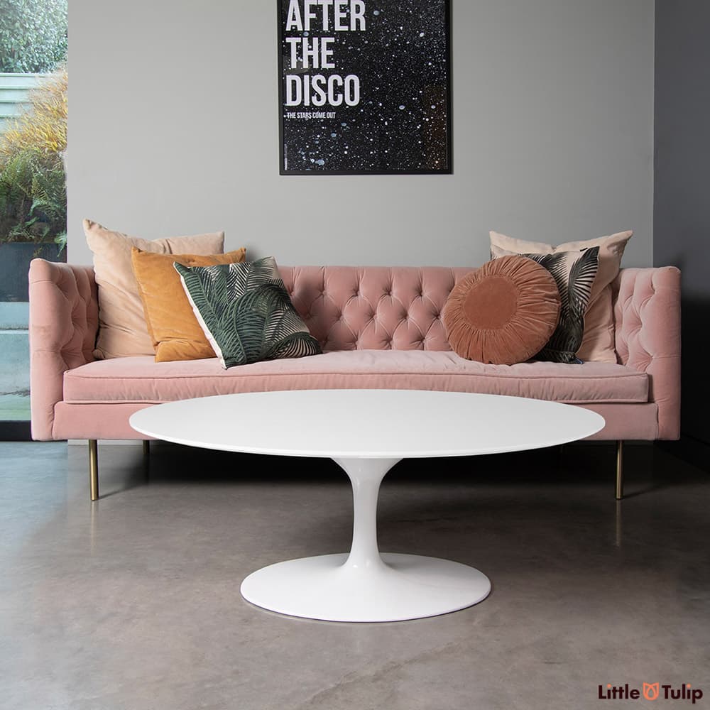 The combination of pink sofa and white laminate Saarinen oval coffee table complement each other perfectly