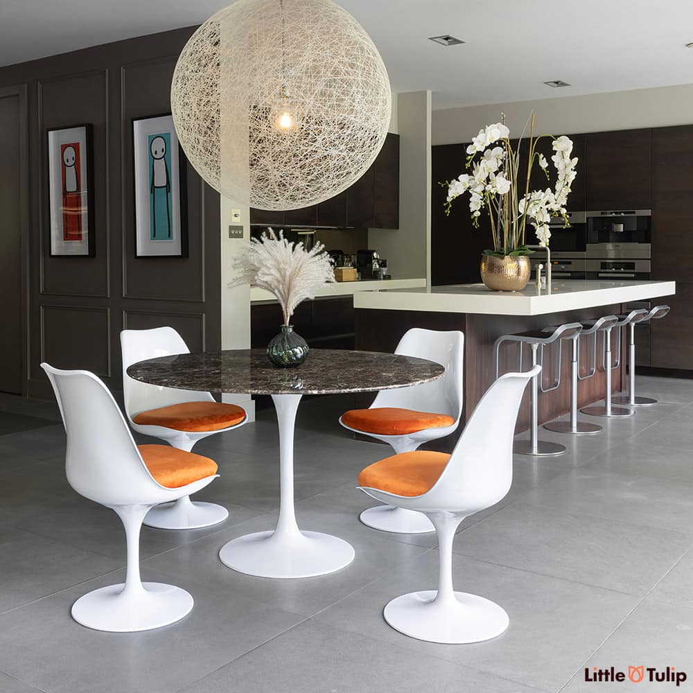 On the edge of the kitchen but still the defining piece is the 120 emperador tulip table with 4 side chairs orange cushions