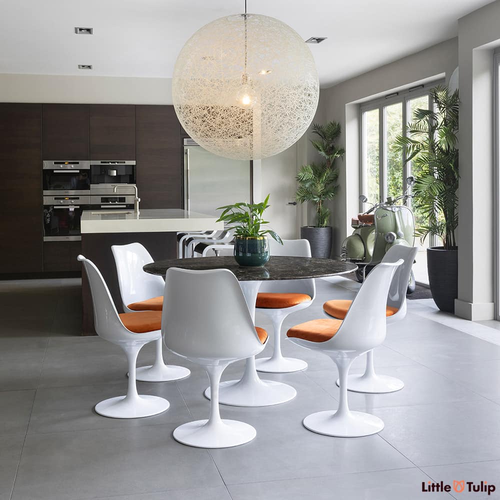 In this open kitchen space, this 120 emperador tulip table and 6 side chairs with orange cushions snuggles comfortably
