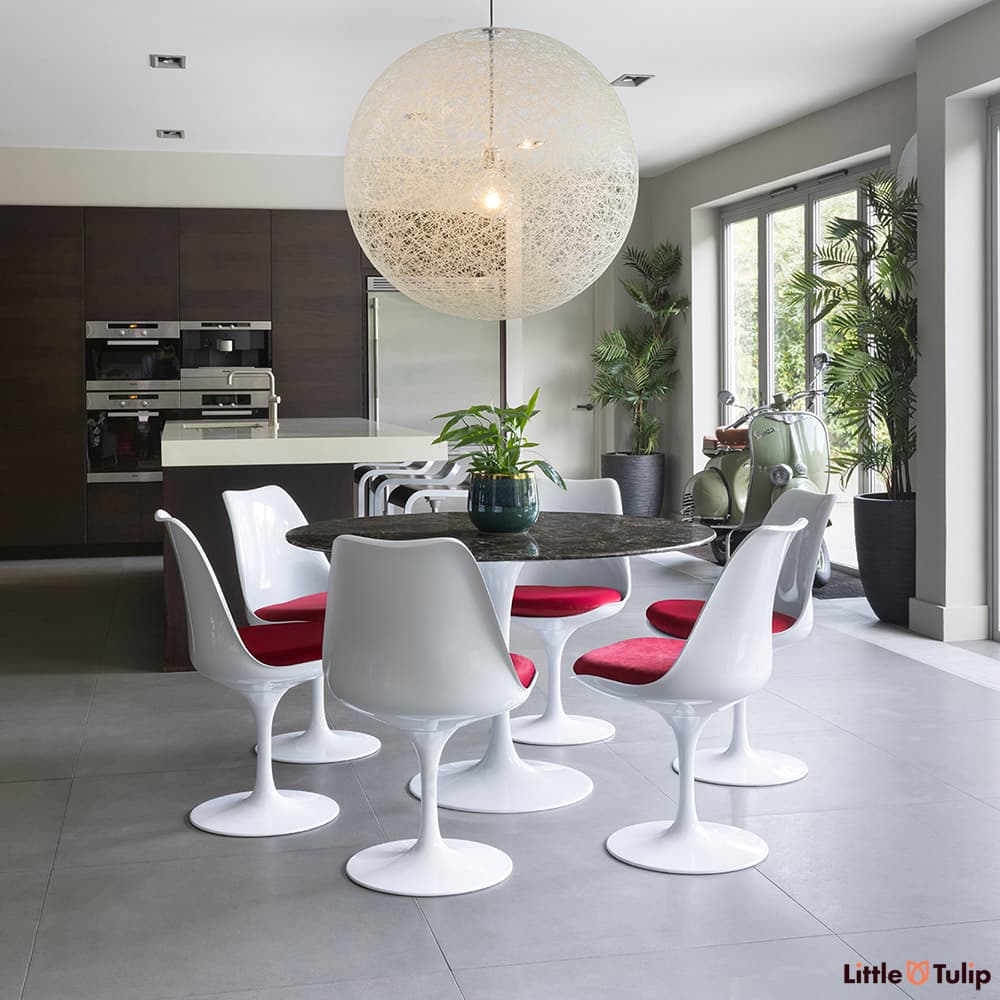 In this open kitchen space, this 120 emperador tulip table and 6 side chairs with red cushions snuggles comfortably