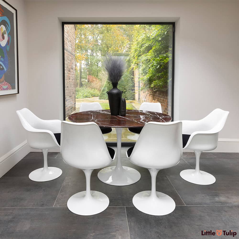 2 Tulip arms, 4 side chairs with black cushion and a 120cm round levanto rosso Saarinen dining table glow in natural light