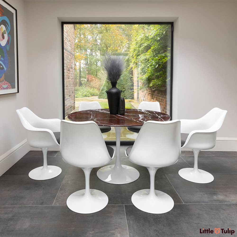 2 Tulip arms, 4 side chairs with grey cushion and a 120cm round levanto rosso Saarinen dining table glow in natural light