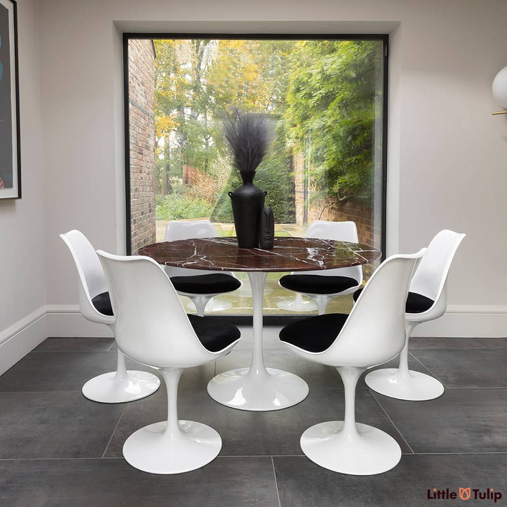 In the natural light sits this 120 levanto rosso Saarinan round dining table and 6 Tulip side chairs with black cushions