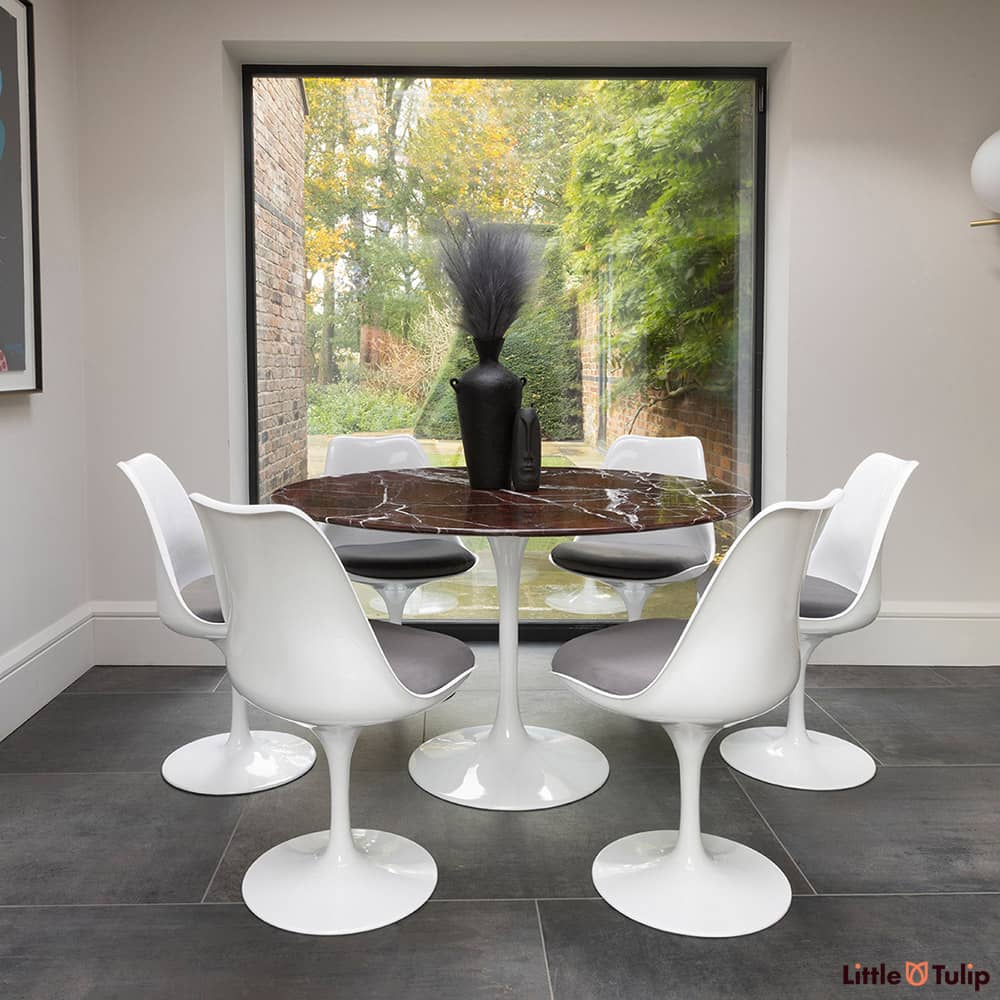 In the natural light sits this 120 levanto rosso Saarinan round dining table and 6 Tulip side chairs with grey cushions