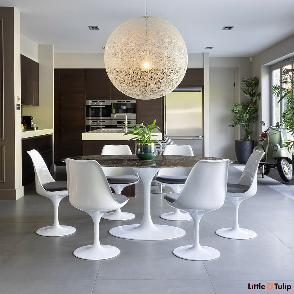 Under a large globe light, the 200 emperador tulip table and 6 chairs with grey cushions exhibit unmatched style.