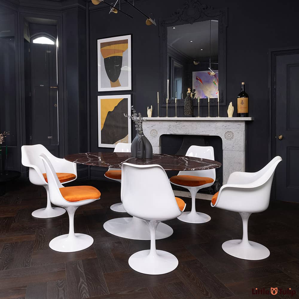 The 170 levanto rosso Saarinen oval dining table, 4 Tulip side chairs, 2 Arms, orange cushions adds colour to this dark room
