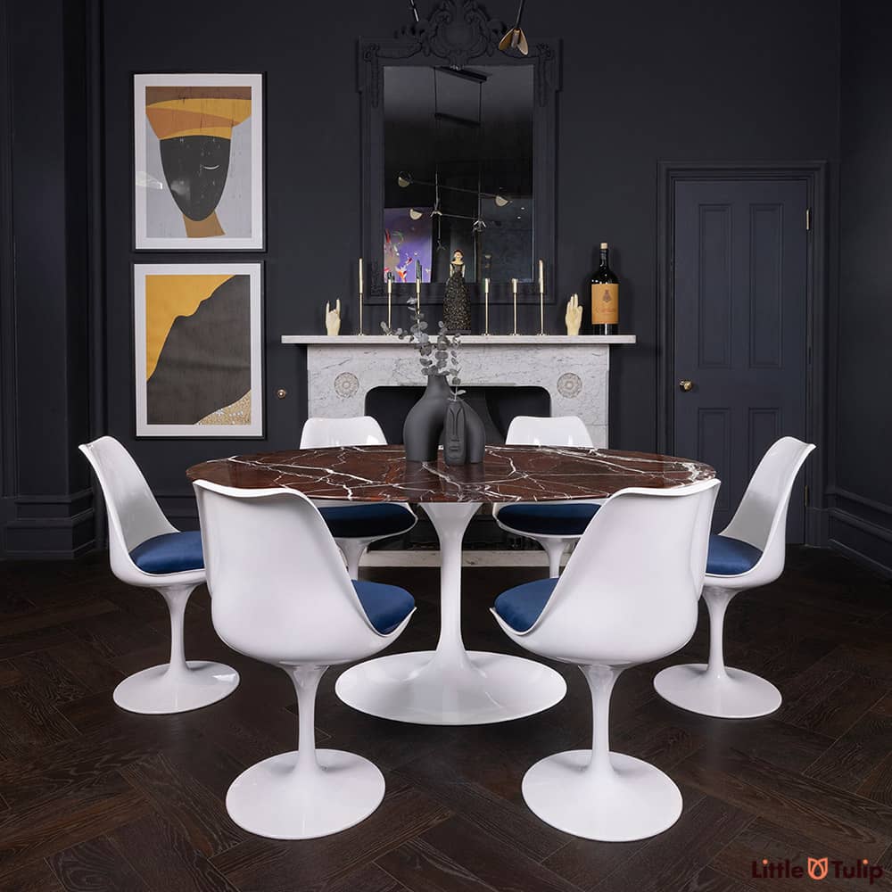 170 levanto rosso Saarinen oval dining table and 6 Tulip side chairs and blue cushions add colour to this dark-themed room