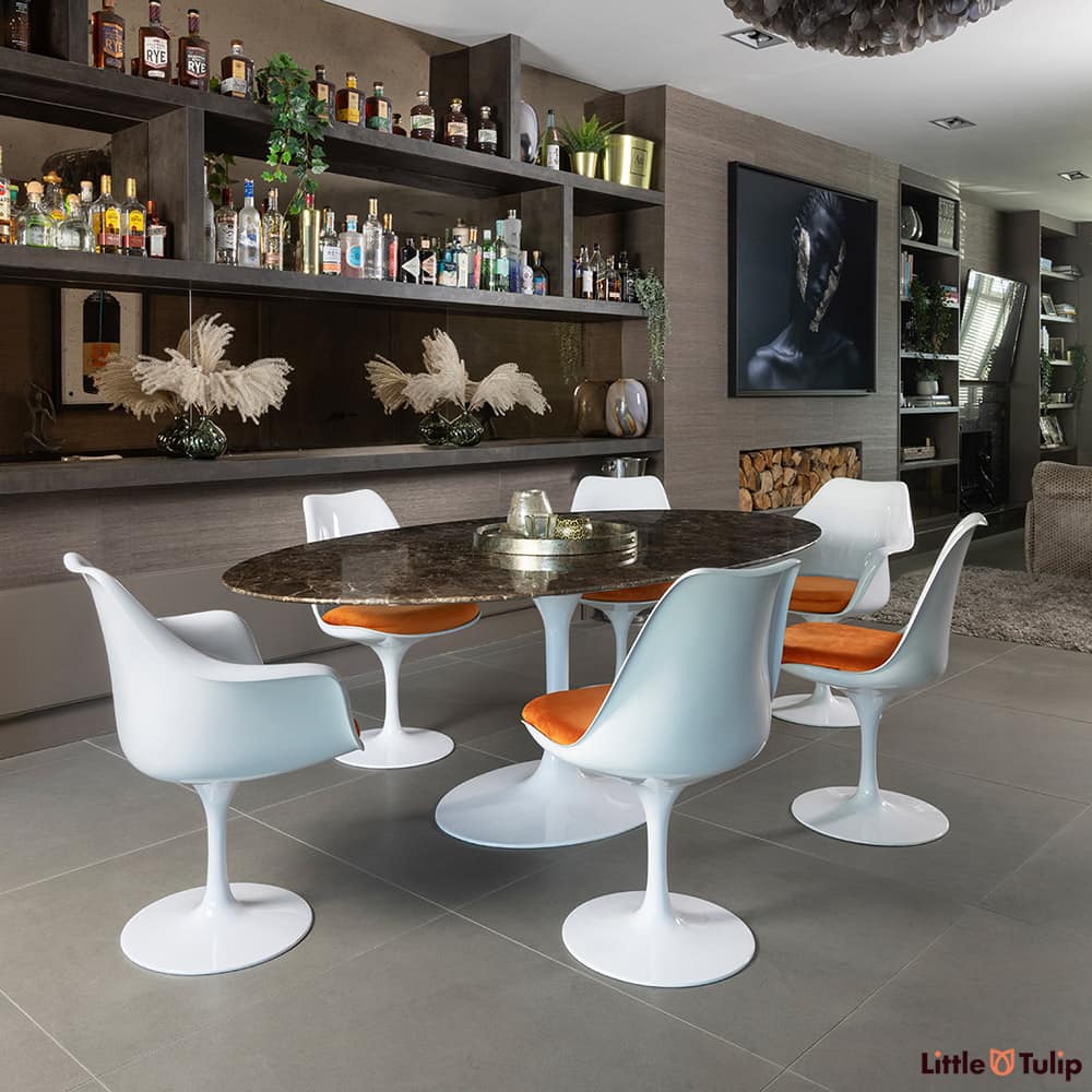 Like living and dining space, this 200 emperador tulip table, 4 sides, 2 arm chairs and orange cushions blend effortlessly