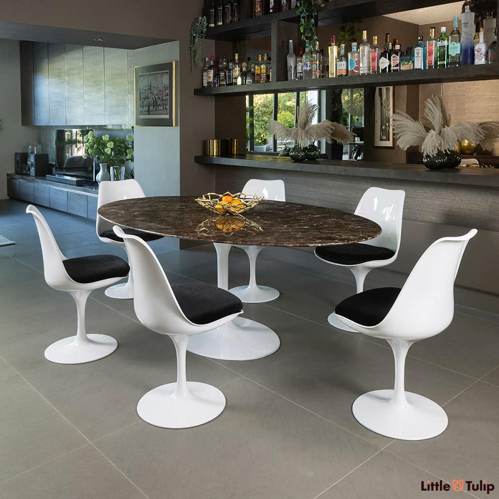 This refined 200 emperador tulip table, 6 chairs, and black cushions exudes sophistication in this elegant space.