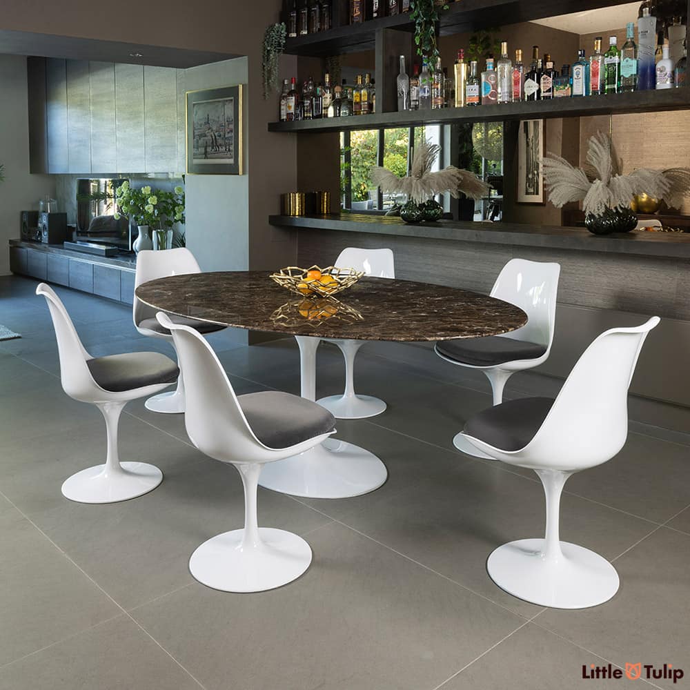 This refined 200 emperador tulip table, 6 chairs, and grey cushions exudes sophistication in this elegant space.