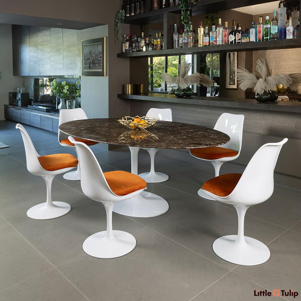 This refined 200 emperador tulip table, 6 chairs, and orange cushions exudes sophistication in this elegant space.