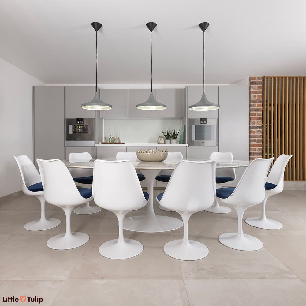 10 white Tulip side chairs and blue cushions surround this gorgeous Arabescato Tulip dining table in a bright, airy kitchen