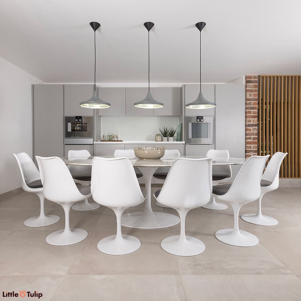 10 white Tulip side chairs and grey cushions surround this gorgeous Arabescato Tulip dining table in a bright, airy kitchen