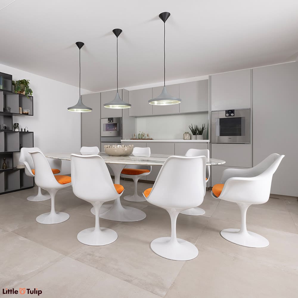 Under the hanging ceiling lights nestles a 244 Arabescato Tulip table with 6 side, 2 arm chairs with comfy orange cushions
