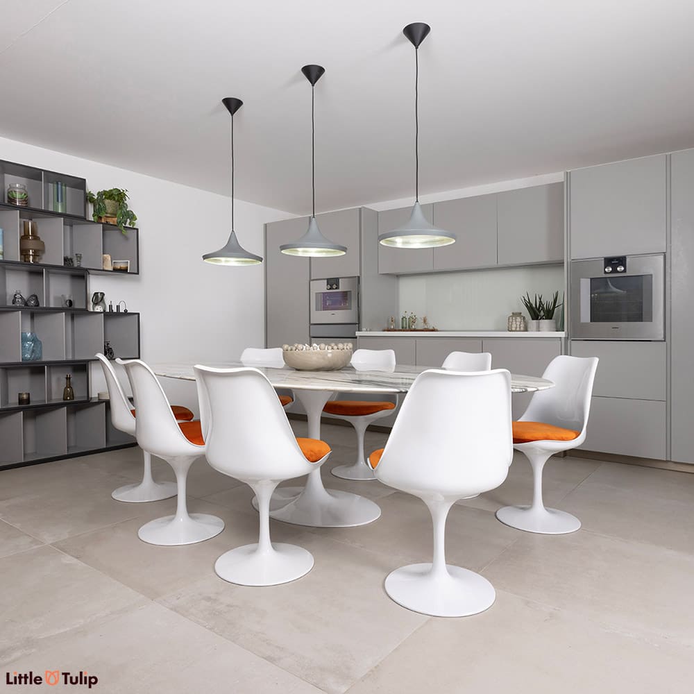 Sat on white tiles, a stunning 244 Arabescato Tulip table with 8 chairs and orange cushions is the rightful centerpiece.