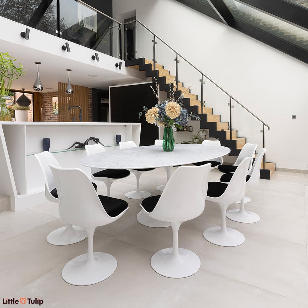 The classic look, a carrara marble Tulip Table with 10 Tulip chairs and black cushions flatters the contemporary dining space
