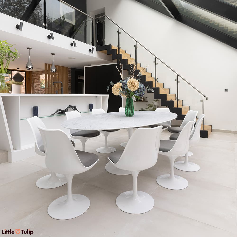 The classic look, a carrara marble Tulip Table with 10 Tulip chairs with grey cushions flatters the contemporary dining space