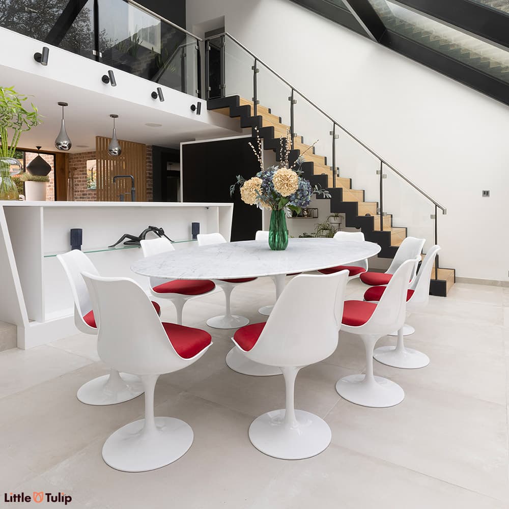 The classic look, a carrara marble Tulip Table with 10 Tulip chairs and red cushions flatters the contemporary dining space