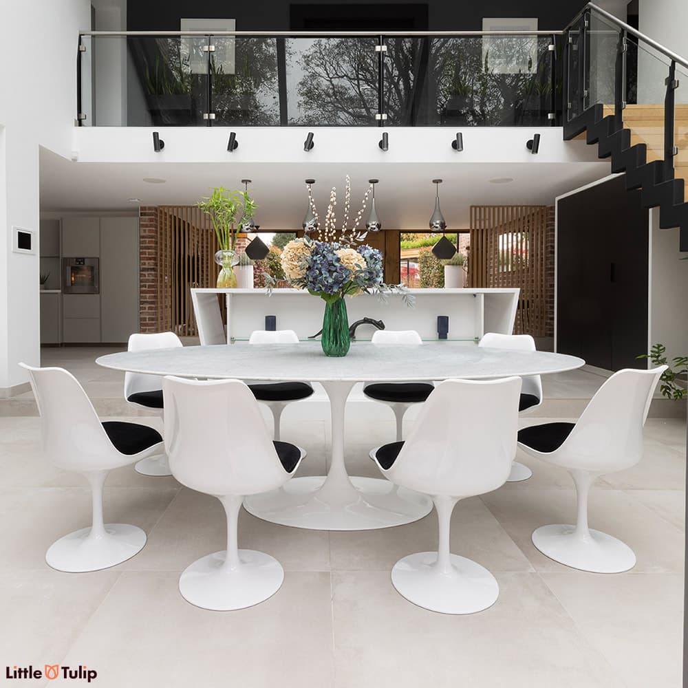 In a fresh kitchen, a bright white Carrara marble Tulip table, 8 chairs with black cushions astound.