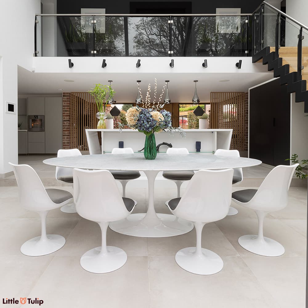 In a fresh kitchen, a bright white Carrara marble Tulip table, 8 chairs with grey cushions astound.