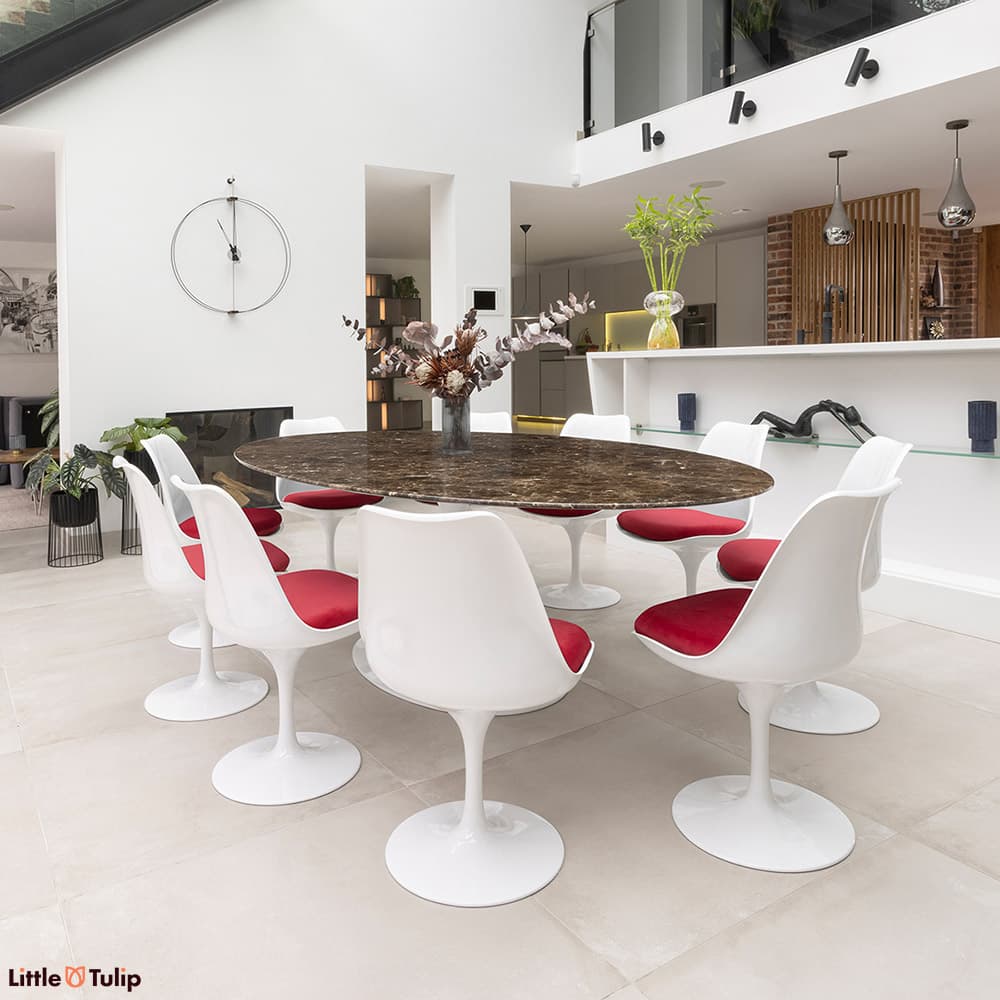 This deep brown Emperador Tulip Table sits with its 10 Tulip side chairs with red cushions in a fantastic open plan space