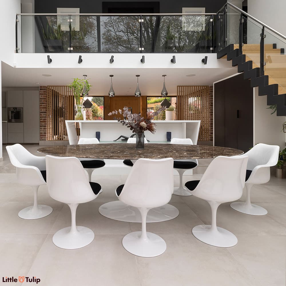 An eye-catching 244 Emperador Tulip table with 6 side, 2 arm chairs and black cushions in a modern open-plan kitchen