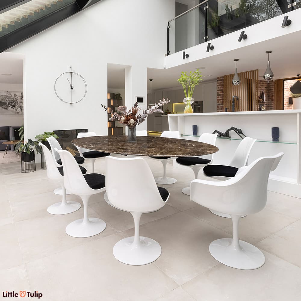 This luxurious emperador 244 tulip table with 8 side and 2 arm chairs with black cushions enriches this all-white kitchen