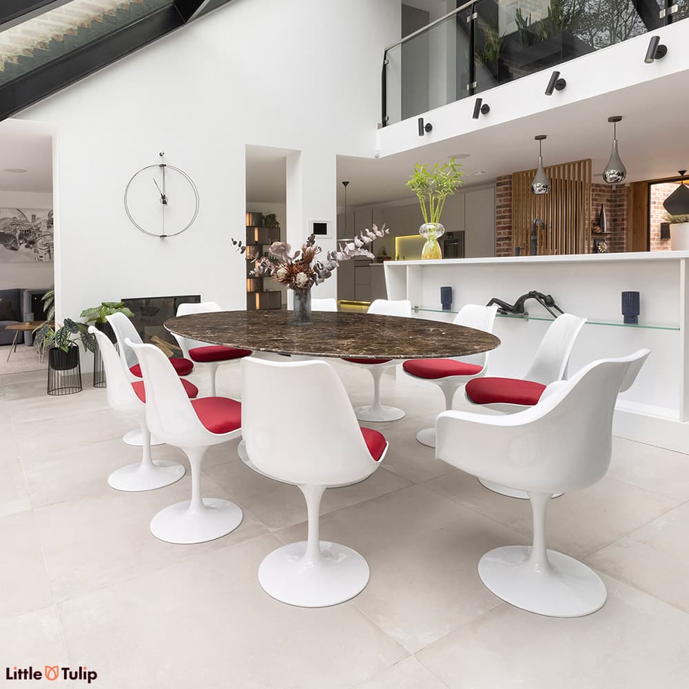 This luxurious emperador 244 tulip table with 8 side and 2 arm chairs with red cushions enriches this all-white kitchen