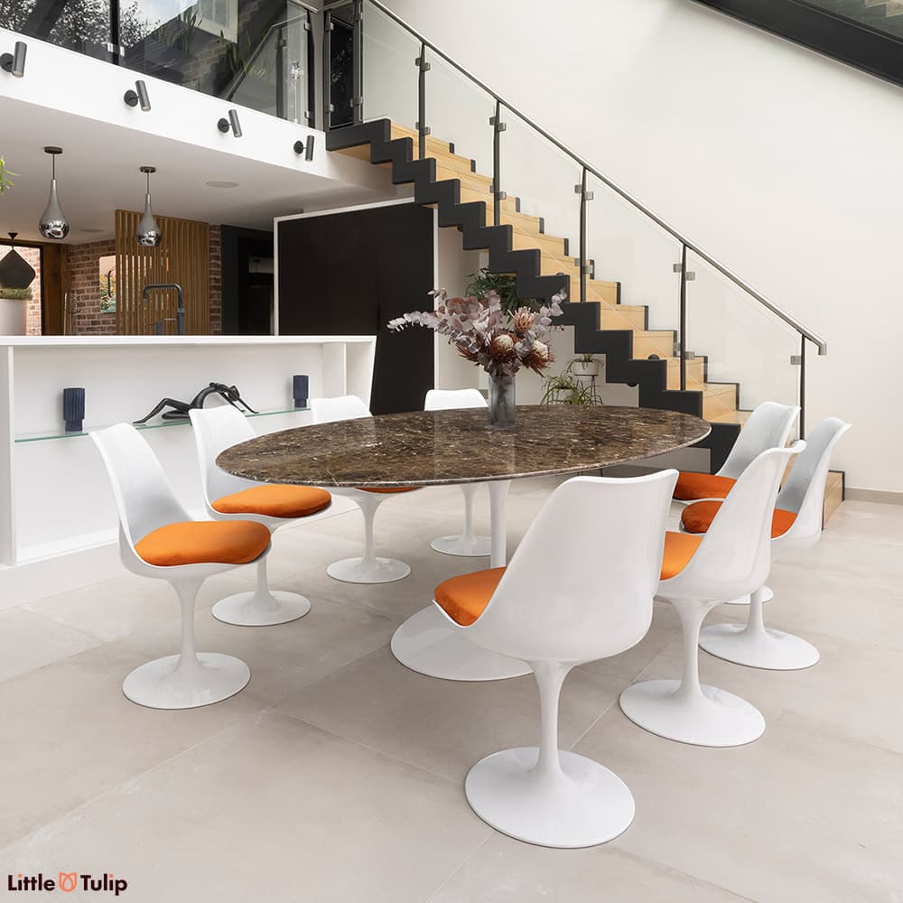 In emperador marble, the 244 tulip table with 8 side chairs and orange cushions is a stunning addition to this modern kitchen