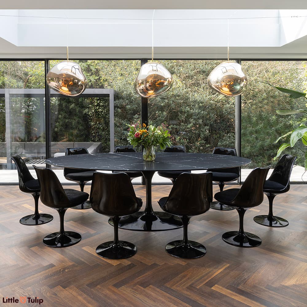 In a complimentary dark themed dining space is a neromarquina Tulip Table with 10 black Tulip side chairs with black cushions