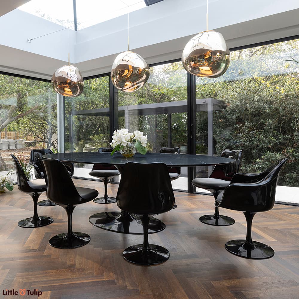 In a wonderfully lit dining space is this neromarquina 244 Tulip table and its 6 side, 2 arm chairs with grey cushions