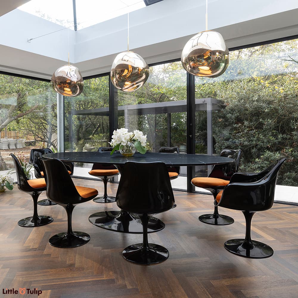 In a wonderfully lit dining space is this neromarquina 244 Tulip table and its 6 side, 2 arm chairs with orange cushions