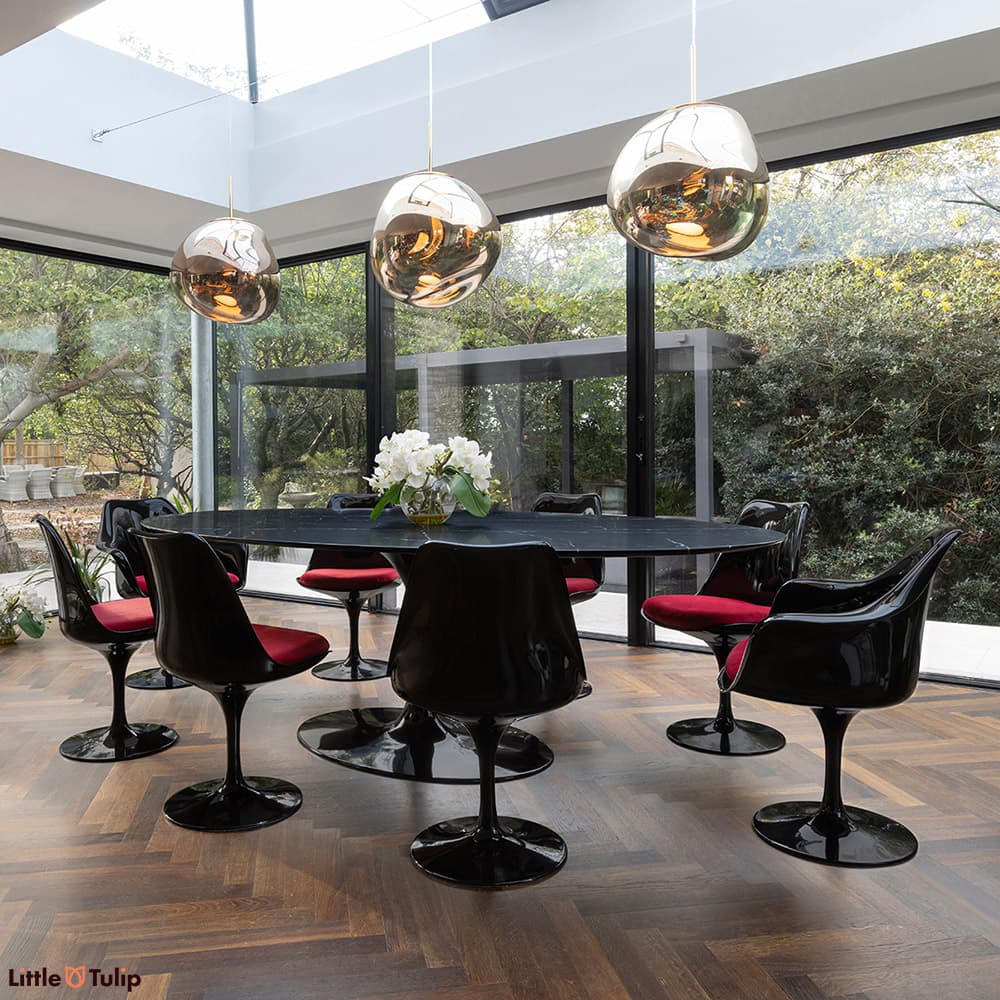 In a wonderfully lit dining space is this neromarquina 244 Tulip table and its 6 side, 2 arm chairs with red cushions