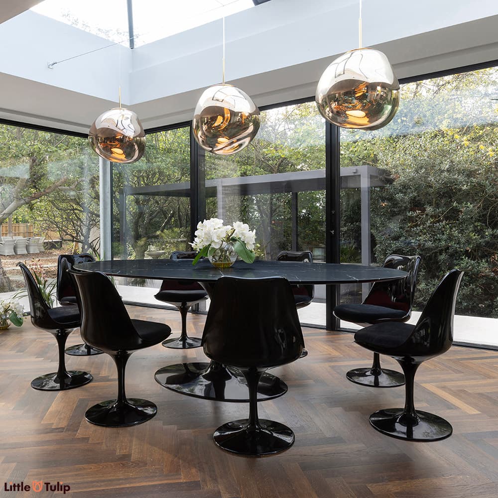 A stunning all black 244 Tulip Table with 8 side chairs and black cushions displayed here in a well-lit natural floor space