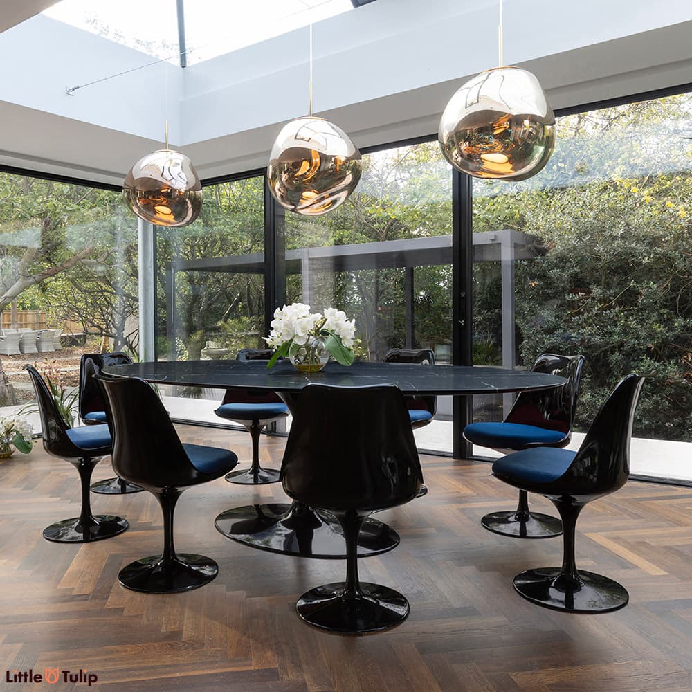 A stunning all black 244 Tulip Table with 8 side chairs and blue cushions displayed here in a well-lit natural floor space